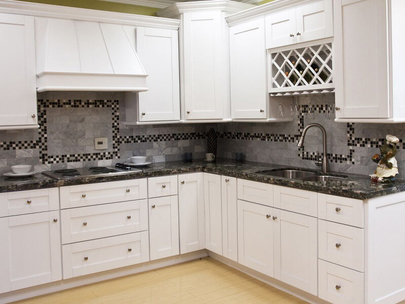 White kitchen cabinets with granite countertops and a tiled backsplash