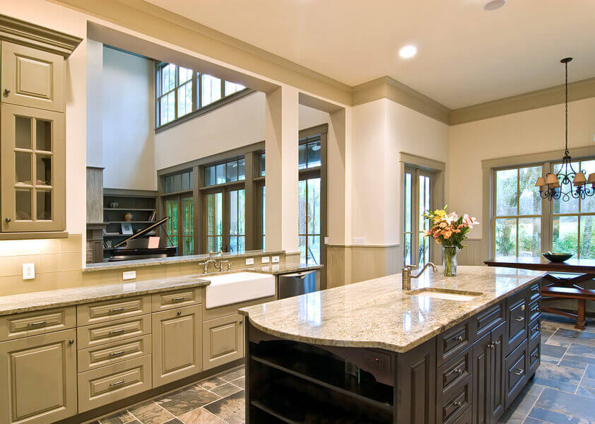 Traditional kitchen with sage green raised panel cabinets, a dark espresso island and granite countertops