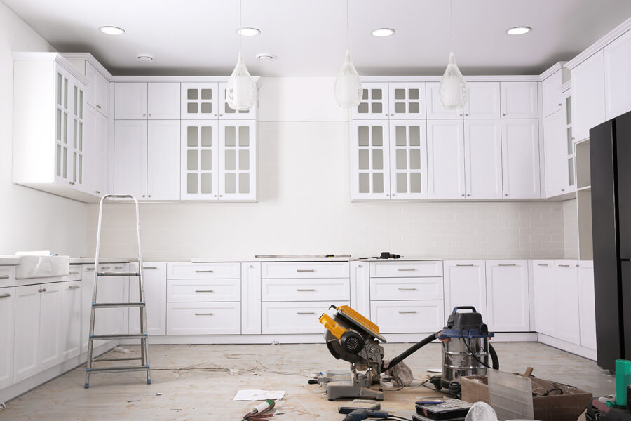 Kitchen renovation underway with new white cabinets being fitted